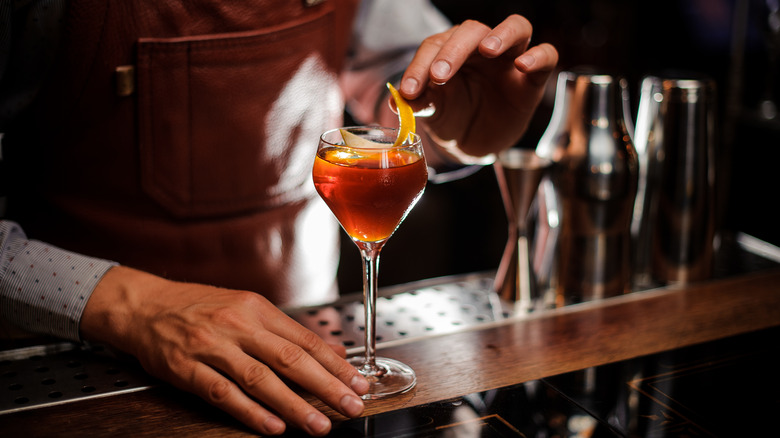 Bartender garnishing cocktail with fruit peel