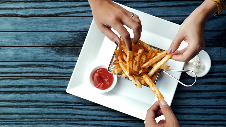 Three hands grabbing some french fries