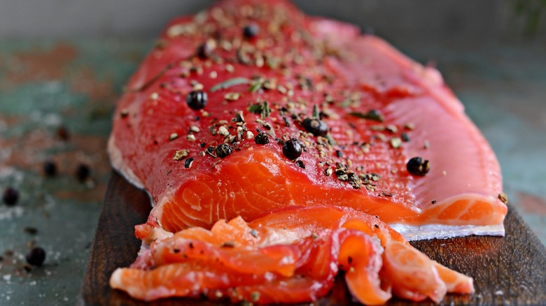 Cured salmon with peppercorns and herbs on a cutting board
