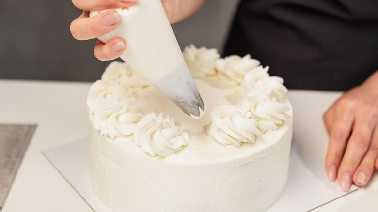 piping frosting onto cake