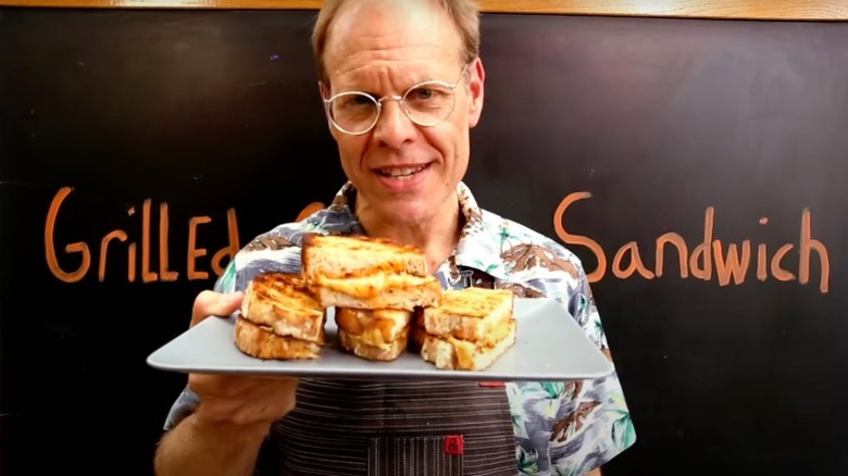 Alton Brown holding a plate of grilled cheese sandwiches