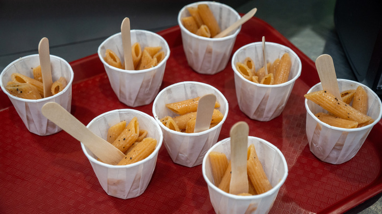 Portions of pasta in sample cups with popsicle stick