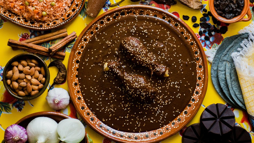 Mole sauce on chicken surrounding by dinner spread