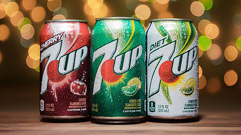 A can of cherry 7UP next to a can of regular 7UP next to a can of diet 7UP
