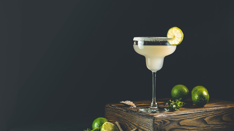 margarita on a wooden crate with limes