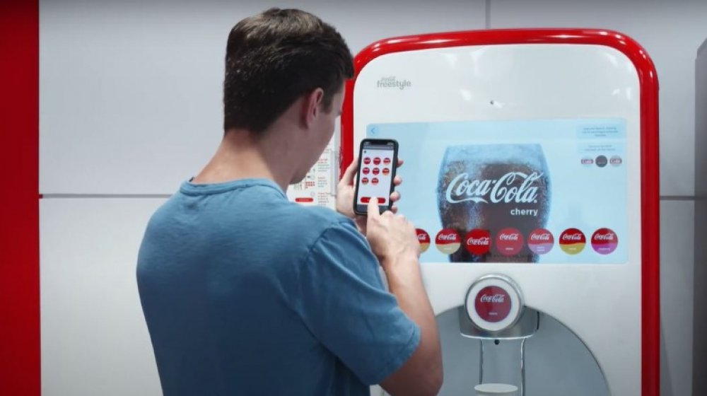 man using coca-cola mobile pour freestyle machine