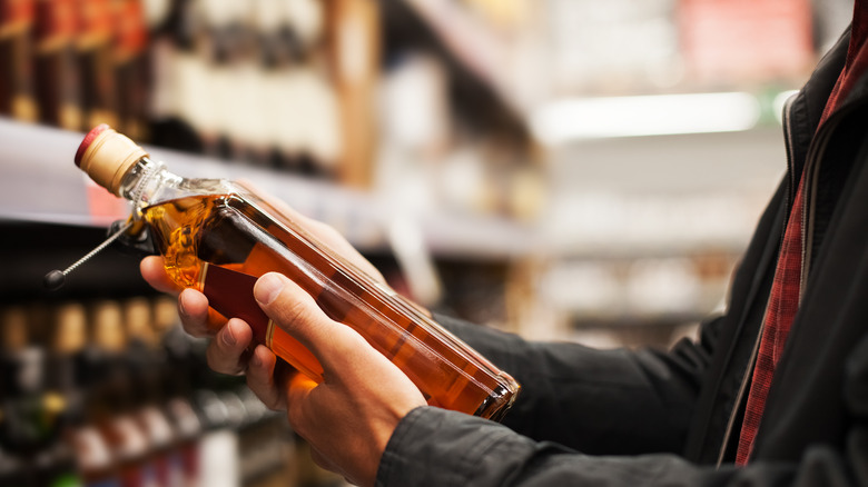 man holds bottle of alcohol