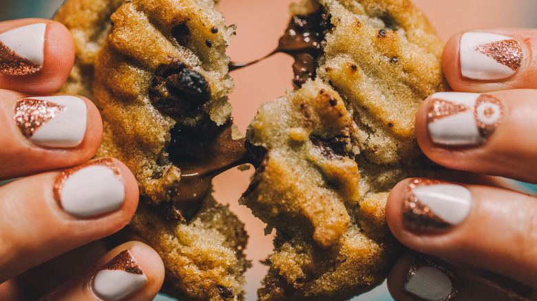 Person holding gooey chocolate chip cookie