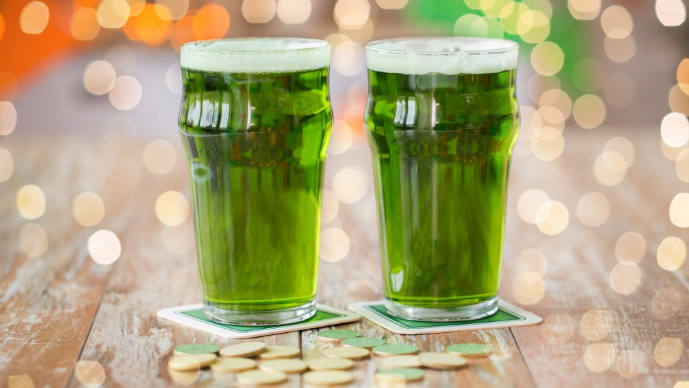 glasses of green beer with gold coins