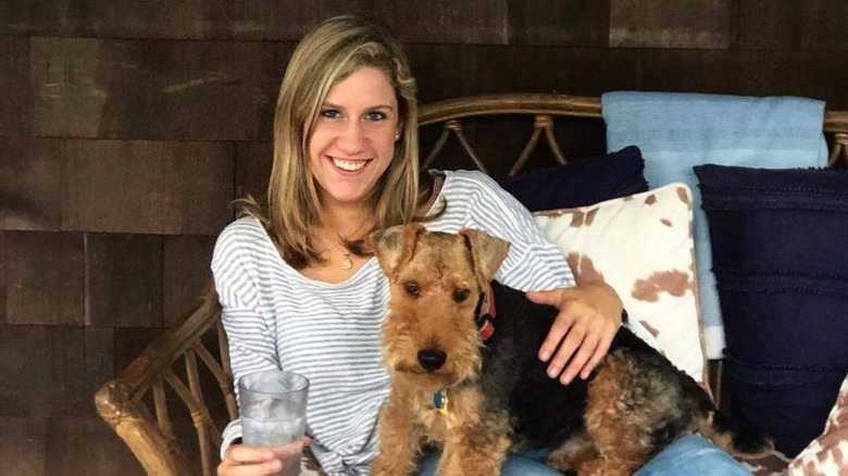 Lidey Heuck with dog on lap sitting in wicker couch