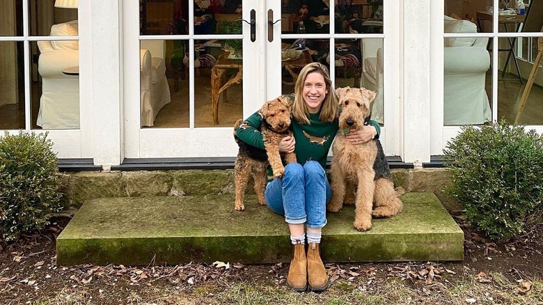 Lidey Heuck sitting on grassy stoop between two dogs
