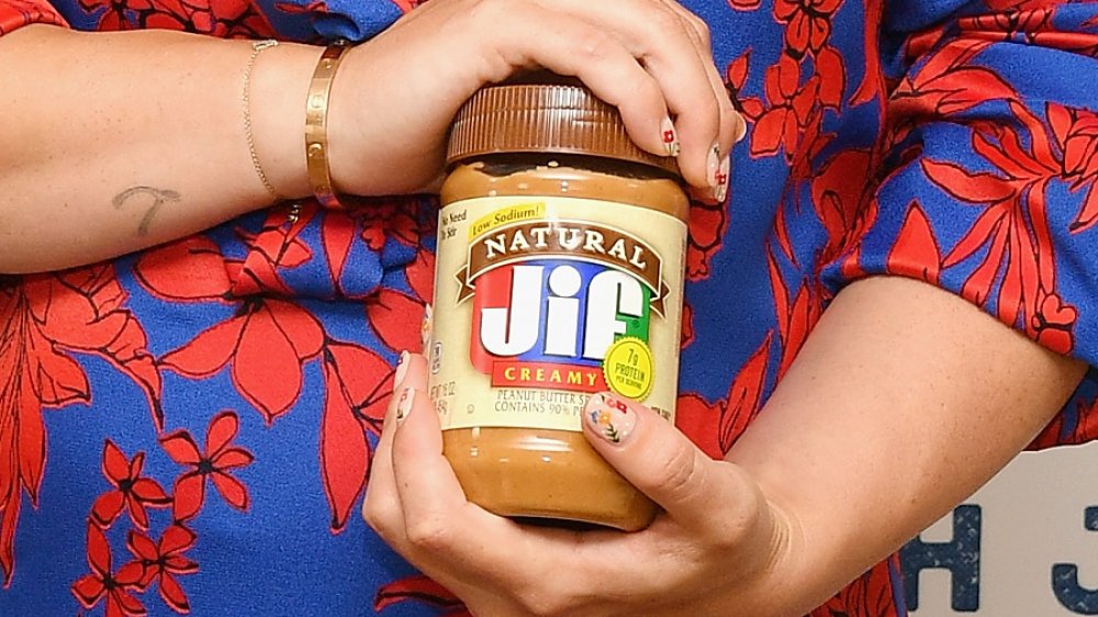 A woman holds a jar of Jif
