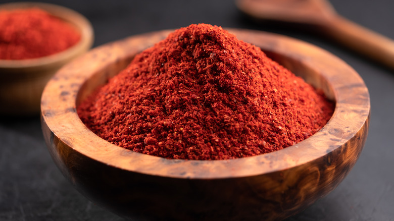 Ground paprika in a wooden bowl with dark background