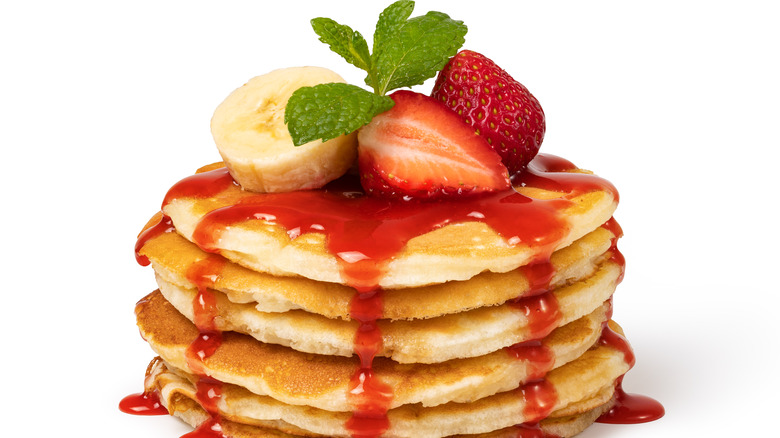 Pancake stack topped with strawberries, banana 