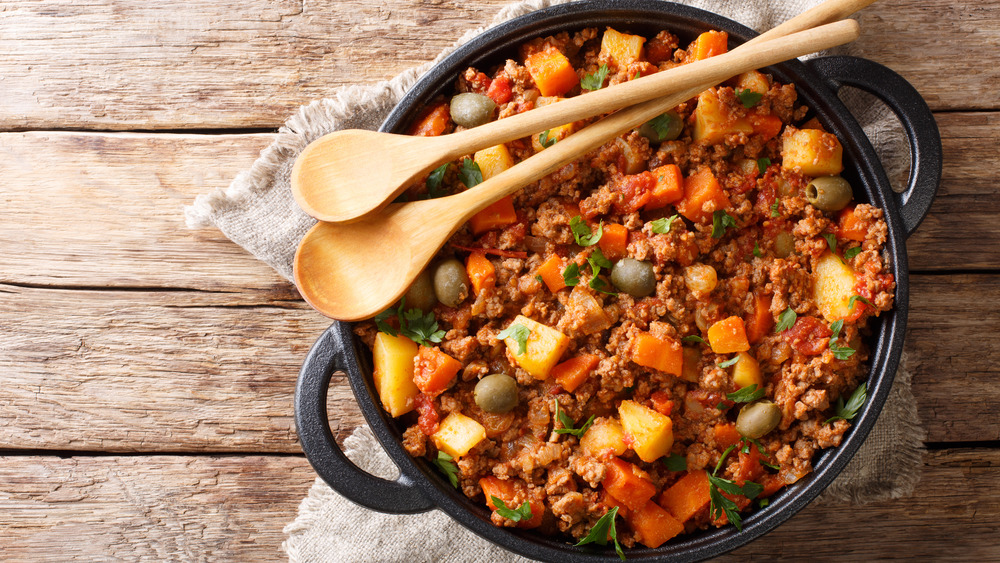 Cuban picadillo in a bowl with wooden spoons, on wooden table