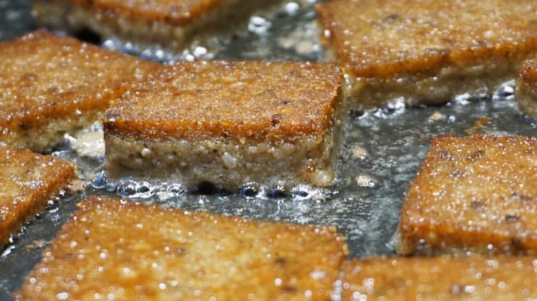 scrapple patties sizzling on black-top grille