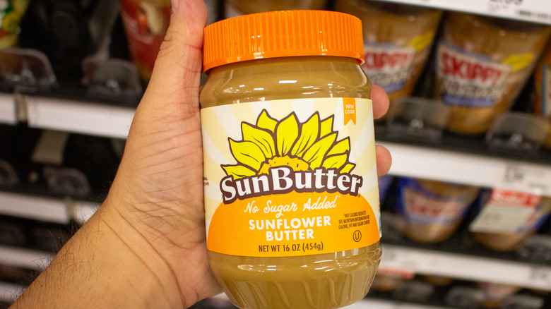 person holding SunButter jar in a grocery store