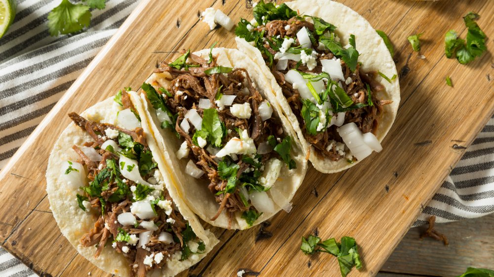 Barbacoa tacos with cilantro, lime, onion and flour tortillas