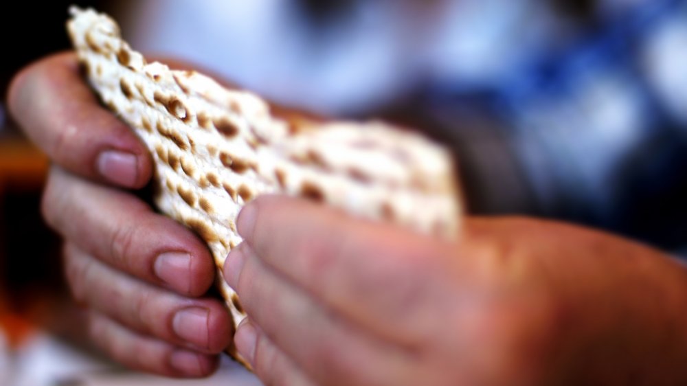 Two hands holding unleavened bread.