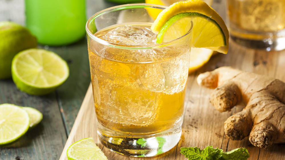 Glass of ginger ale with pieces of ginger and a slice of lime