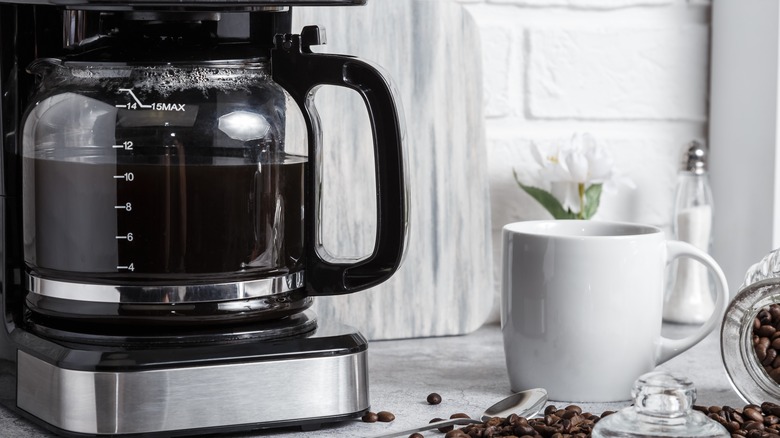 Coffee maker with coffee brewing and a cup on a counter
