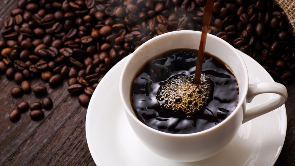 coffee beans behind a cup of black coffee