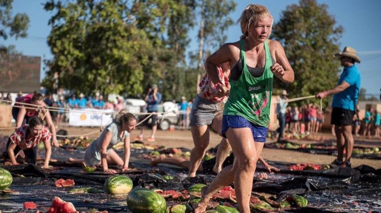 Women running through broken water melons 