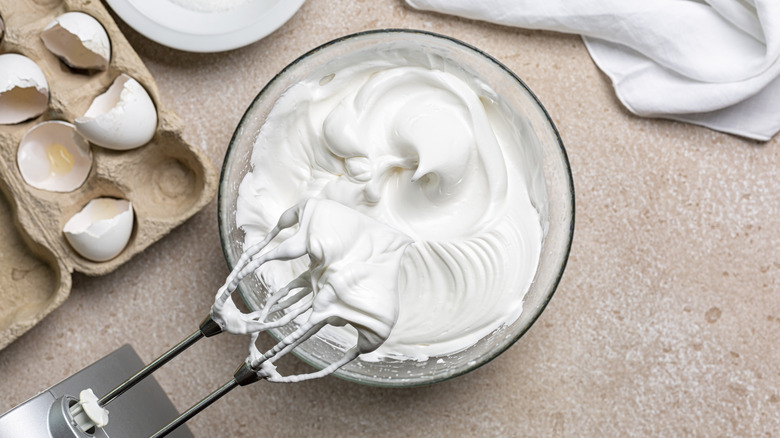 Egg whites freshly beaten into a meringue with an electronic mixer hovering over them..