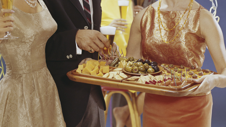 Photo of a woman holding tray of hors d'oeuvres with two party guests