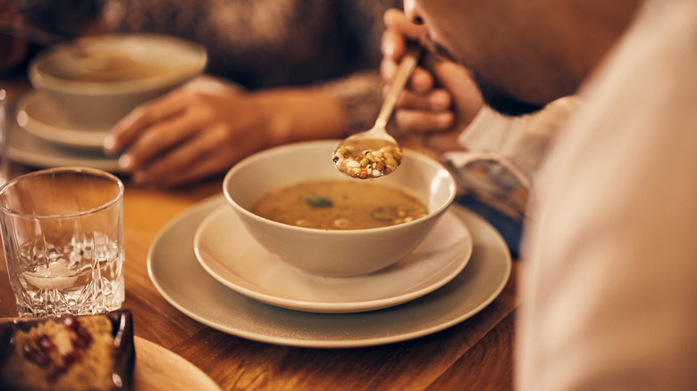 person eating soup at home