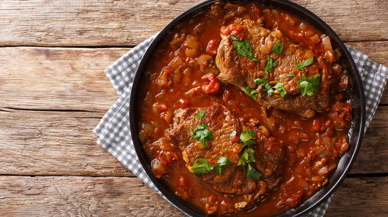 Overhead shot of plate of Swiss steak on wooden table.