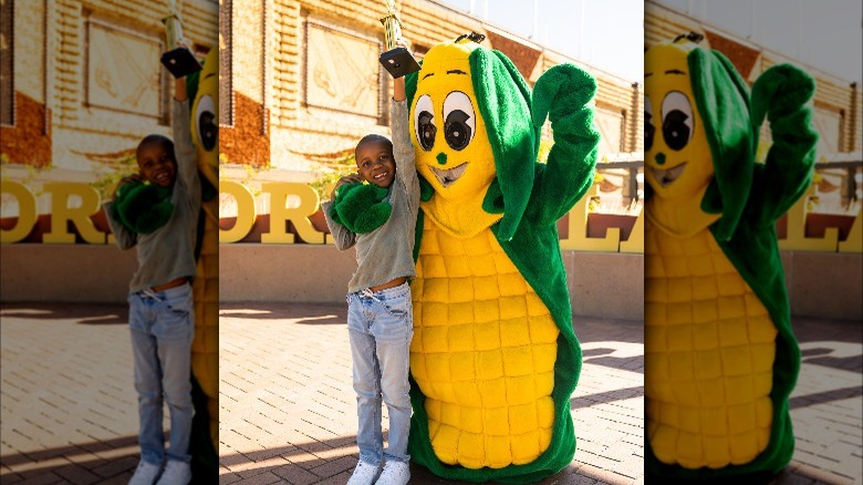 Corn kid Tariq with trophy and corn mascot