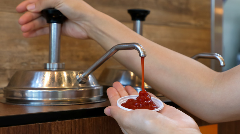person using self serve ketchup pump