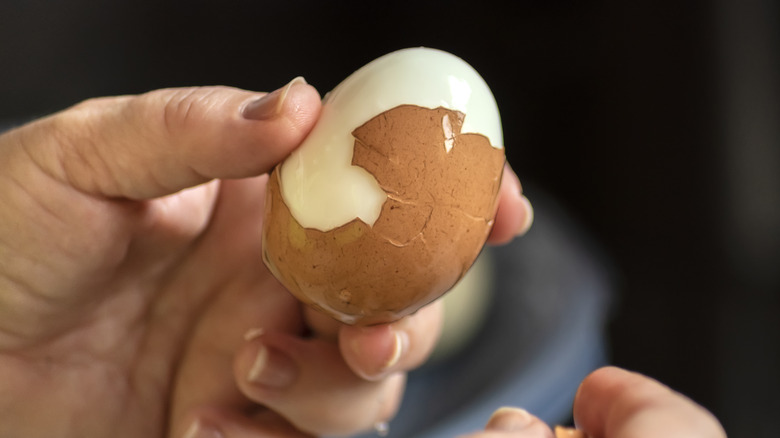 Hands peeling hard-boiled eggs