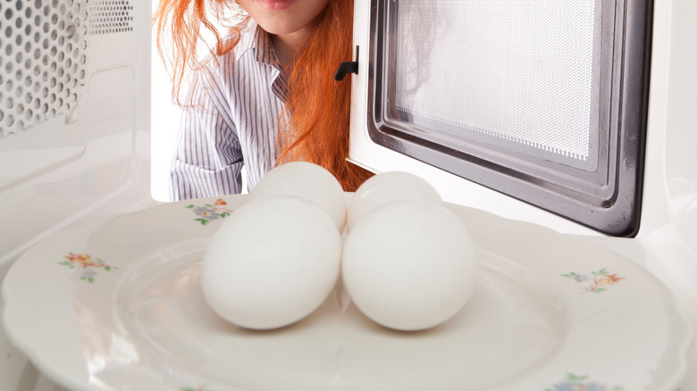 Redhead putting eggs in microwave