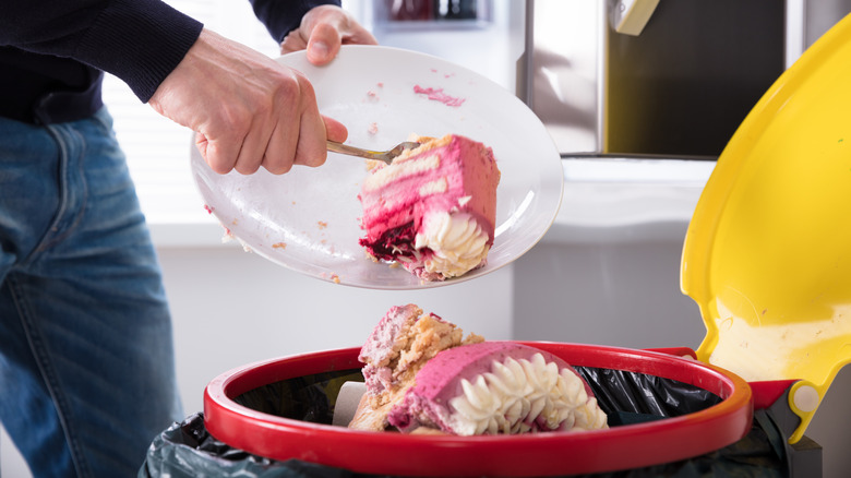 Person throwing cake in garbage