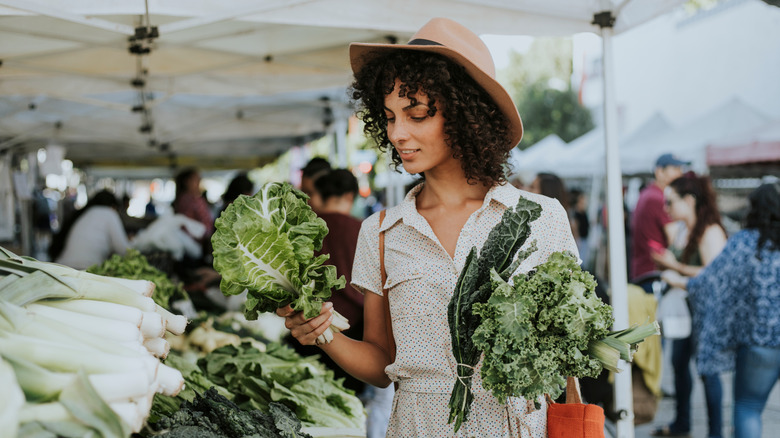 Person buying leafy greens in a white outfit