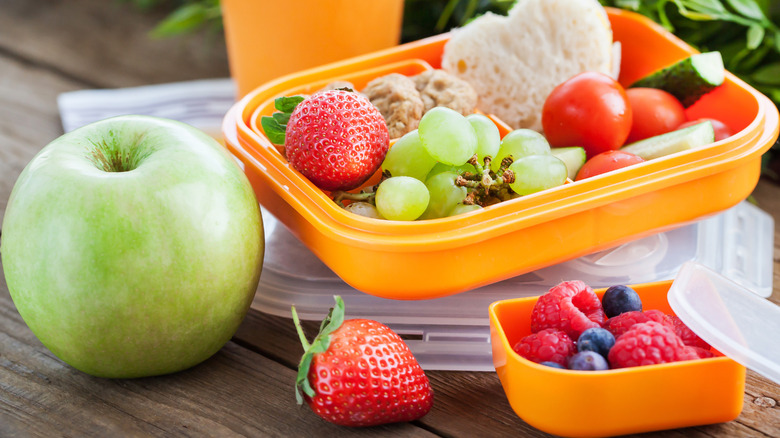 Strawberries and grapes in yellow plastic container