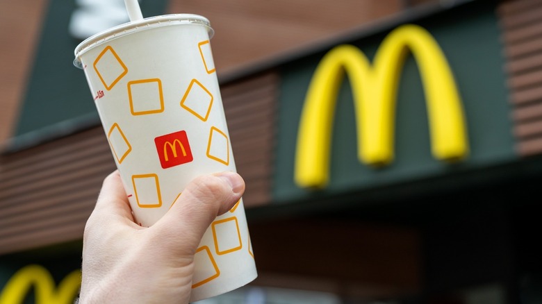 hand holding mcdonald's cup with logo in background