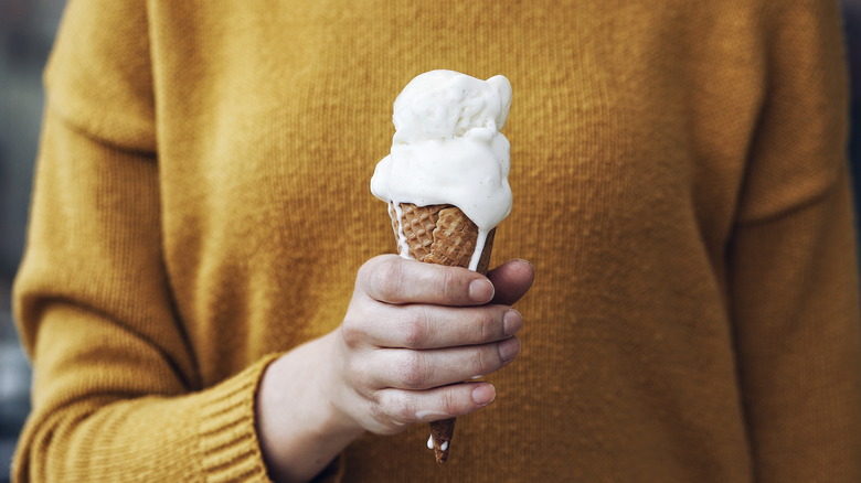 person holding melting ice cream cone