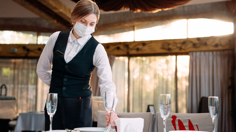 Person setting table at restaurant