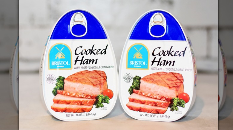 Two unopened cans of Bristol brand cooked ham on table