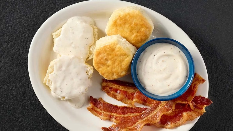 A plate with biscuits, gravy, and bacon from Cracker Barrel.