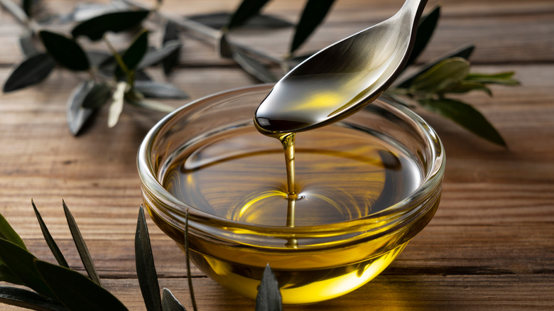 Olive oil dribbling from spoon into bowl