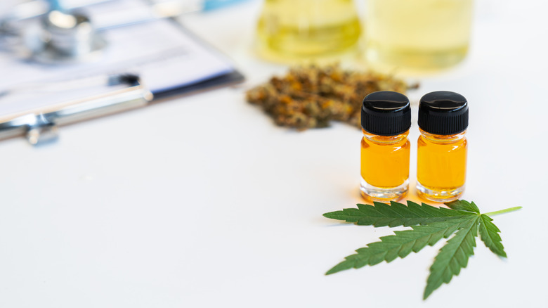 Small bottles of oil next to a cannabis leaf