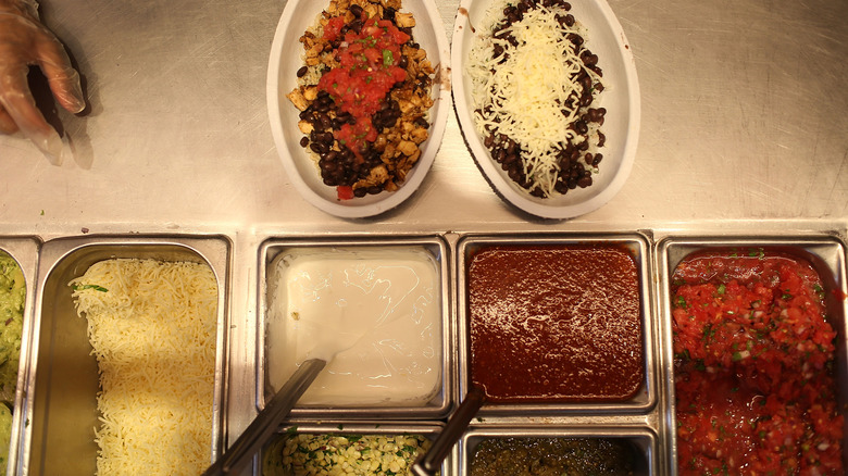 Chipotle bowls next to containers of salsa