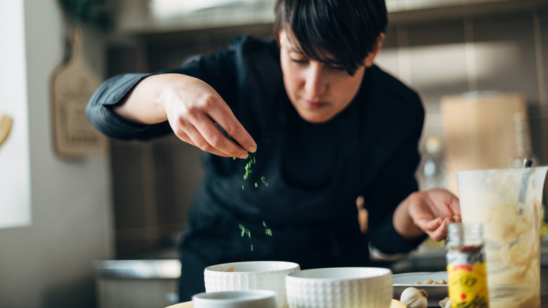 Chef sprinkling parsley on dish