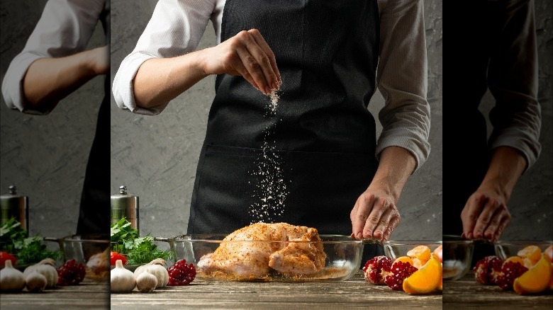 Chef seasoning chicken with salt