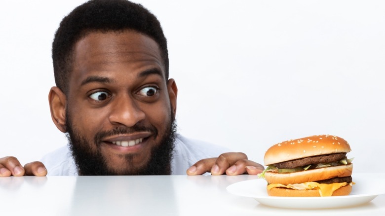 Man eyeing hamburger on plate