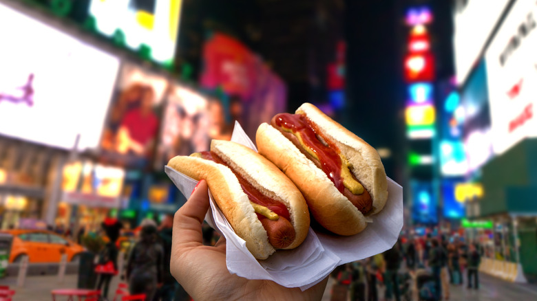 Person holding hot dogs in Times Square